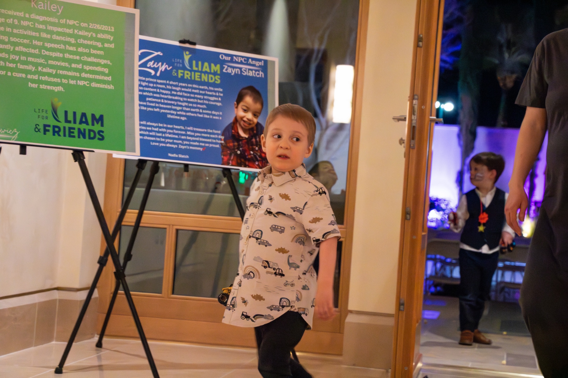 Liam at the Starlight Soirée in front of NPC family posters